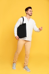 Full length portrait of young man with eco bag on yellow background