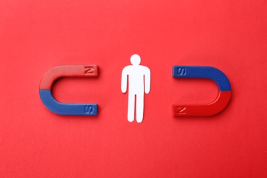 Photo of Magnets attracting paper man on color background, top view. Business rivalry concept