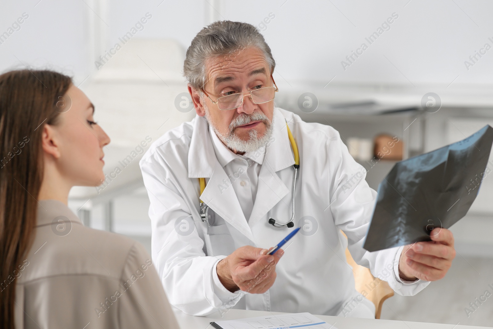 Photo of Orthopedist showing X-ray picture to patient in clinic