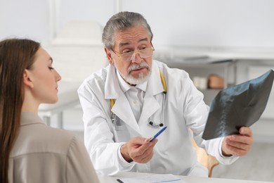 Orthopedist showing X-ray picture to patient in clinic