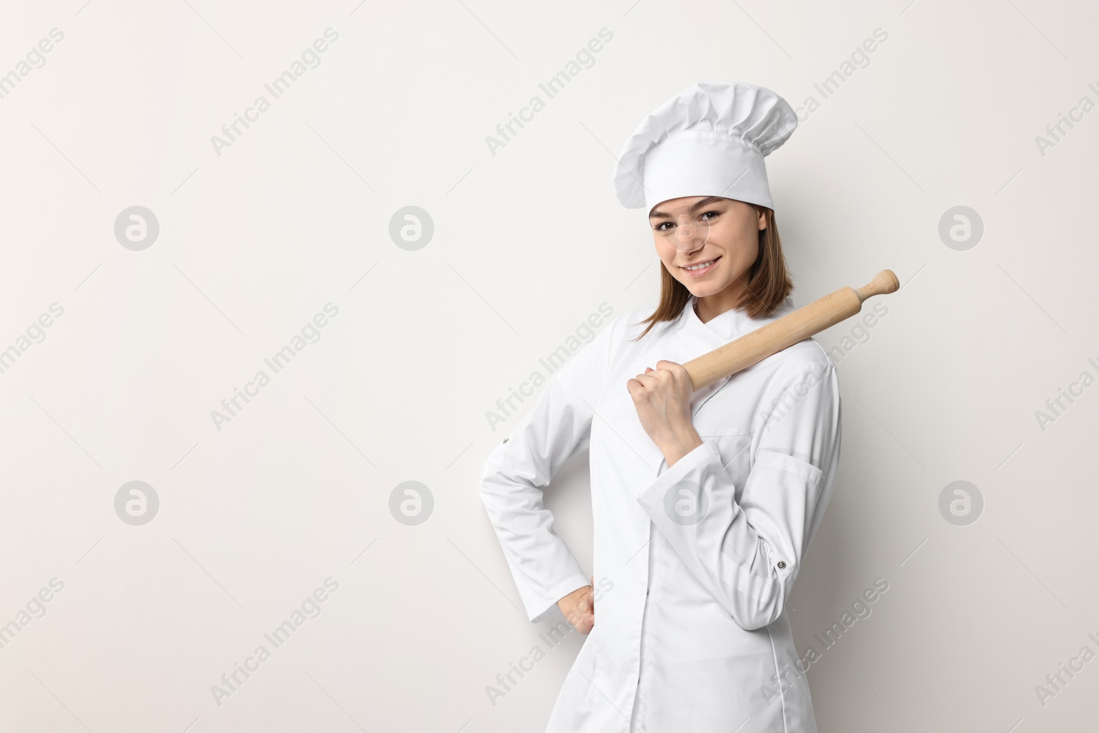 Photo of Professional chef with rolling pin on light background. Space for text