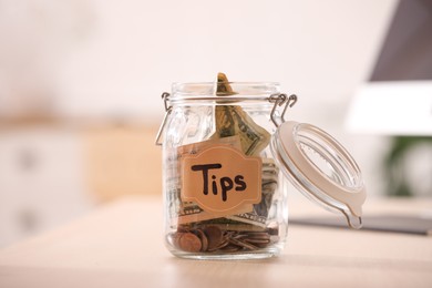 Photo of Glass jar with tips on wooden table indoors, closeup