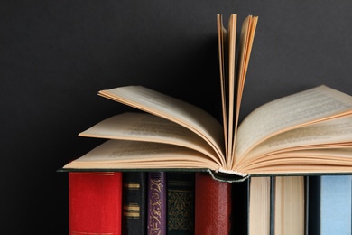 Photo of Different hardcover books against black background, closeup