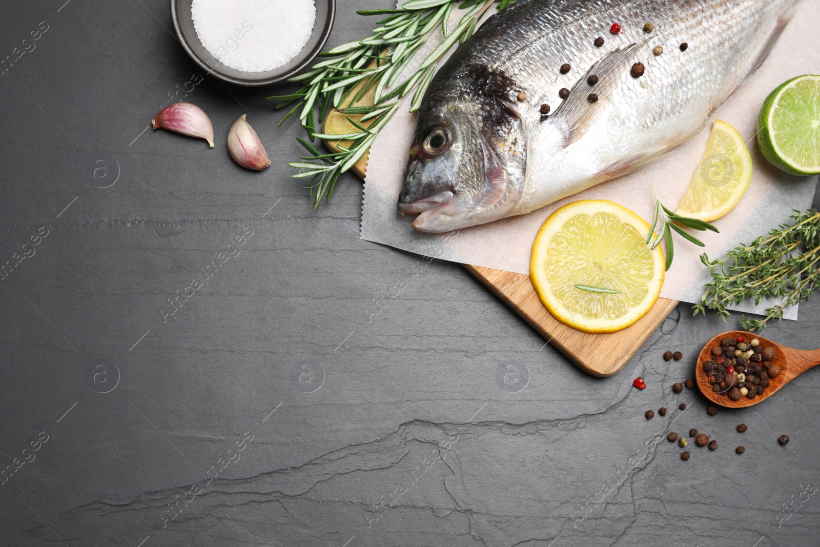 Photo of Flat lay composition with fresh raw dorado fish and ingredients on black table, space for text