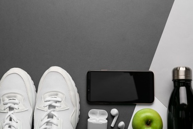 Photo of Flat lay composition with smartphone and sport equipment on color background. Space for text