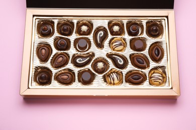 Photo of Box of delicious chocolate candies on pink background, closeup