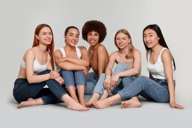 Group of beautiful young women sitting on light grey background