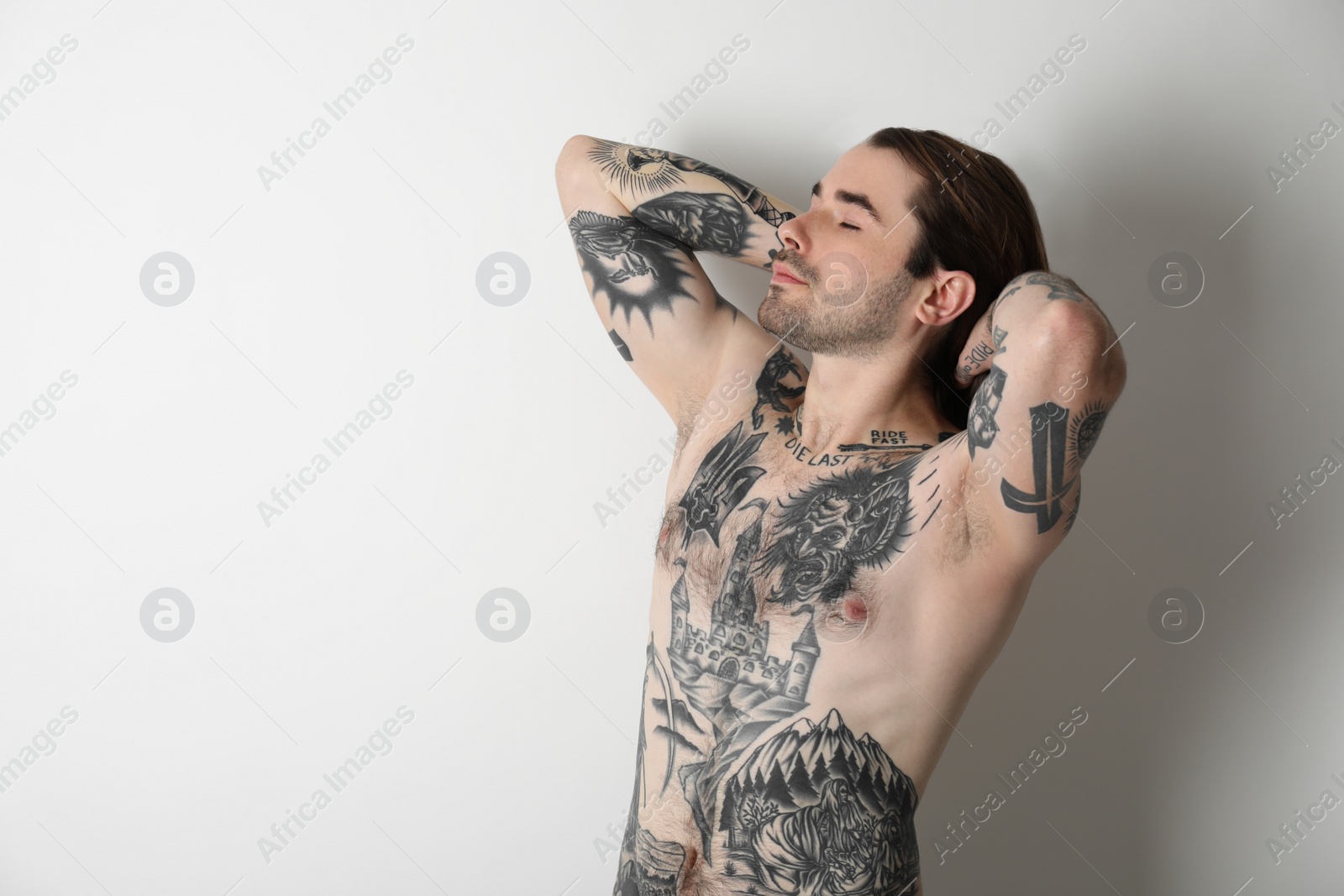 Photo of Young man with tattoos on body against white background