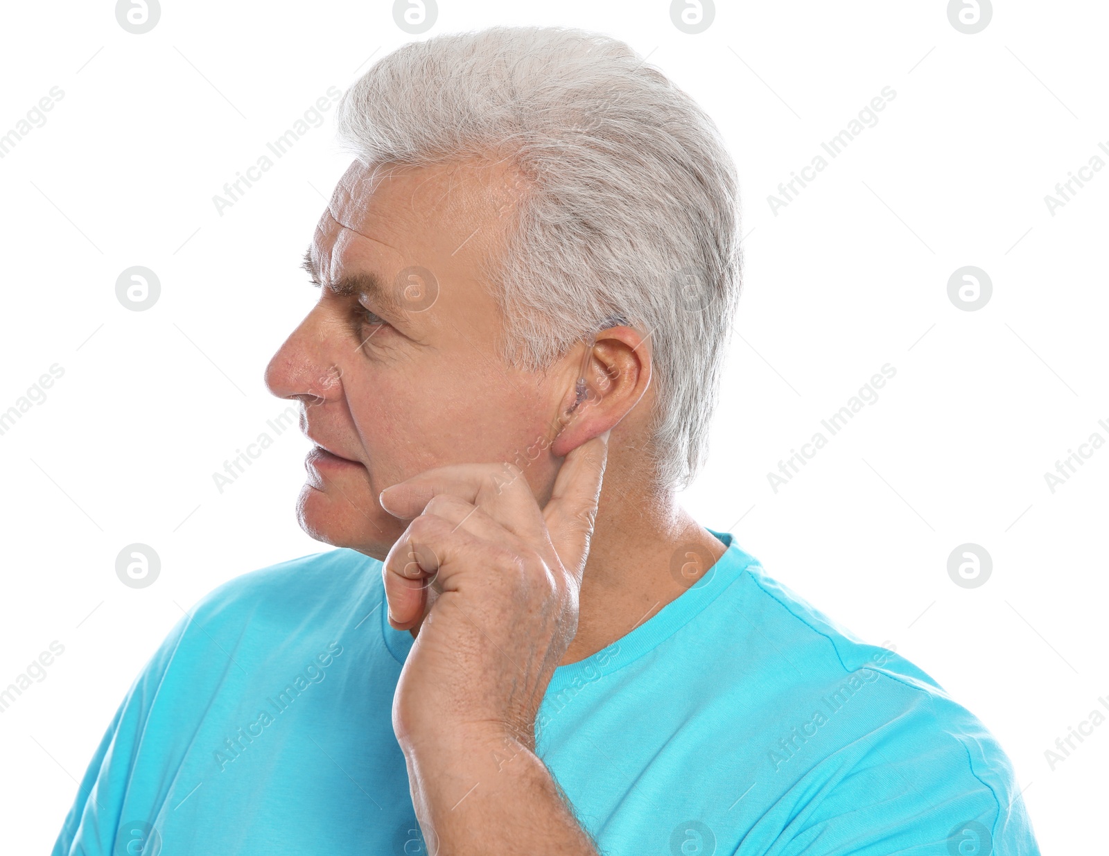 Photo of Mature man adjusting hearing aid on white background