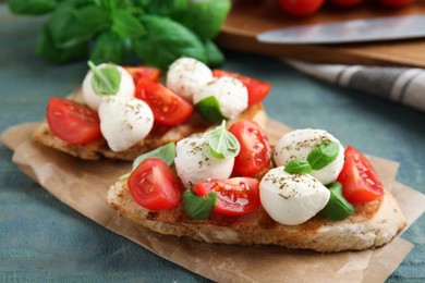 Delicious sandwiches with mozzarella, fresh tomatoes and basil on blue wooden table