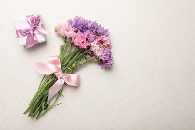 Photo of Bouquet of beautiful cornflowers and gift box on light table, flat lay. Space for text