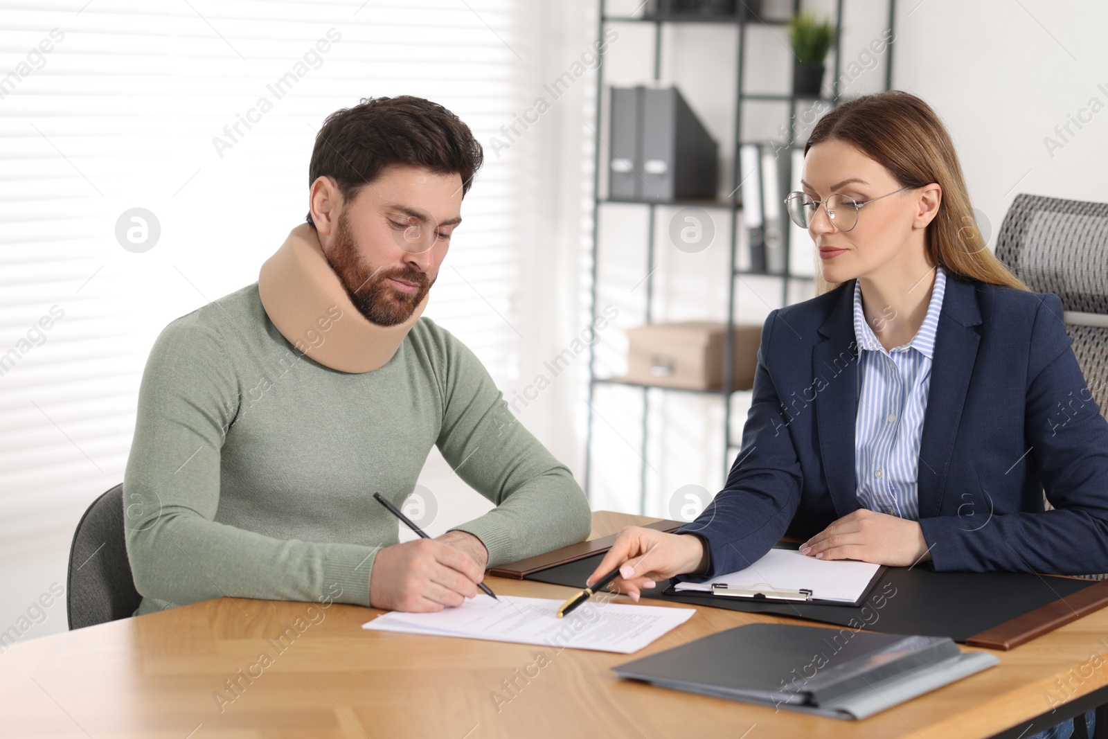 Photo of Injured man signing document in lawyer's office