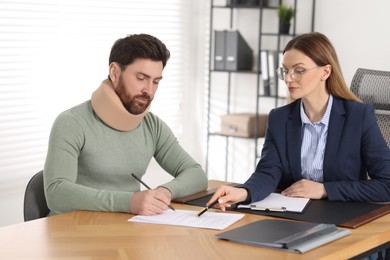 Injured man signing document in lawyer's office