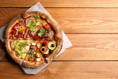 Slices of different delicious pizzas on wooden table, top view. Space for text