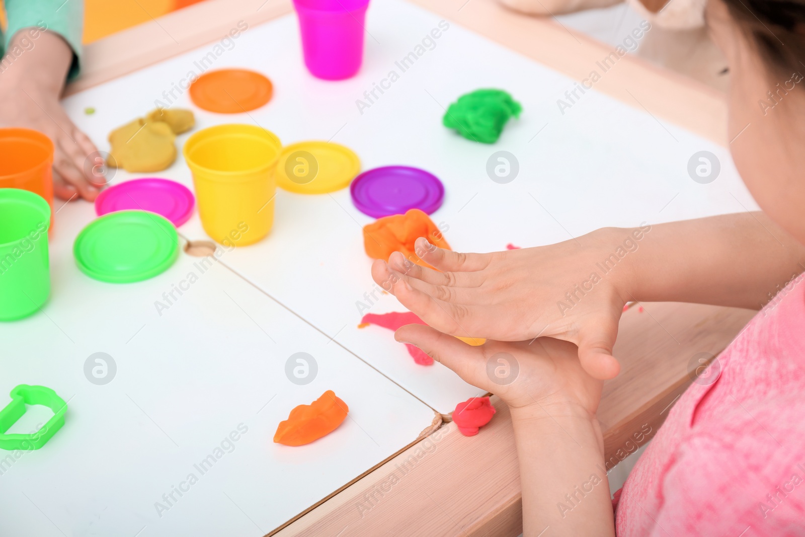 Photo of Cute little girl using play dough at table, closeup