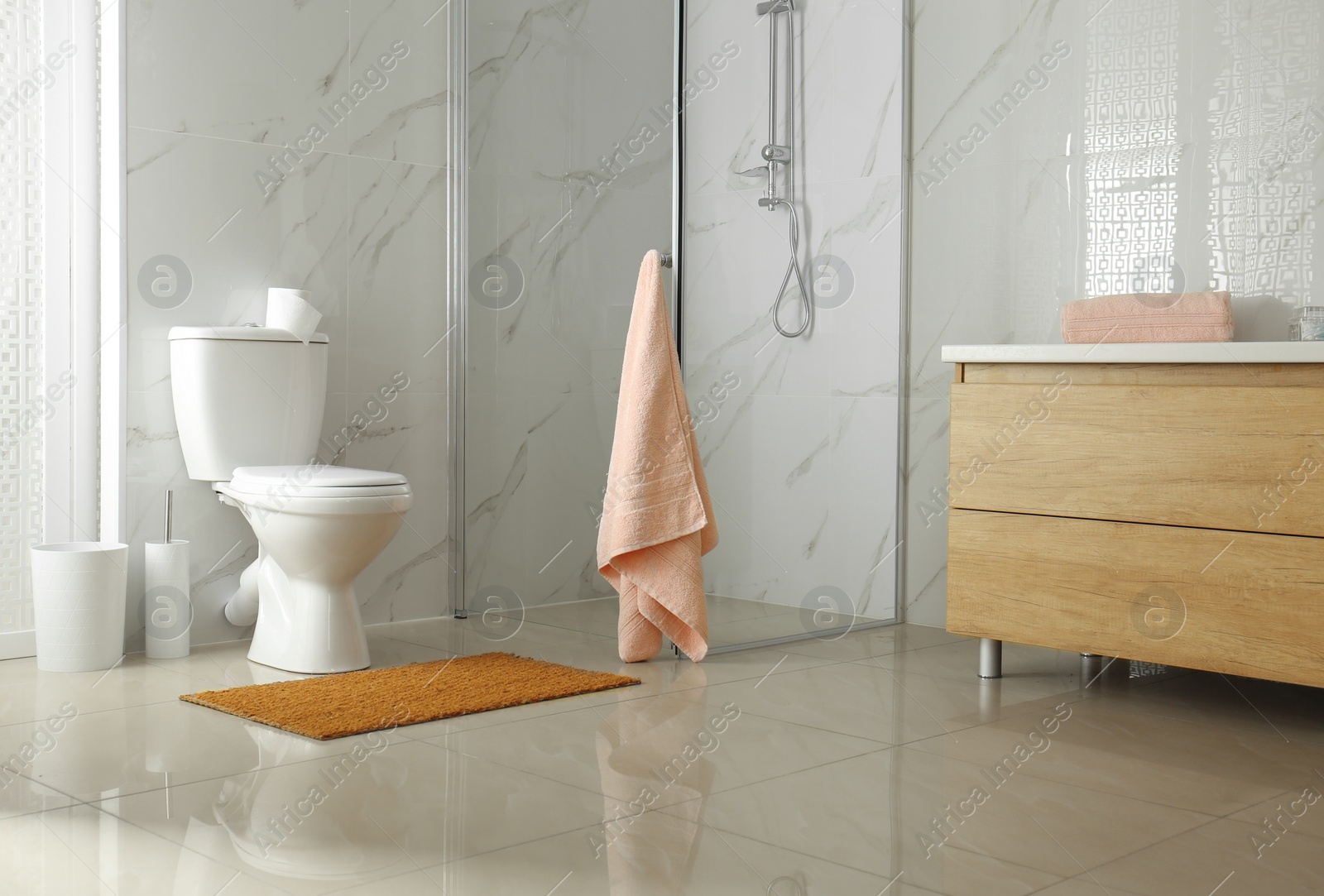 Photo of Toilet bowl near shower stall in modern bathroom interior