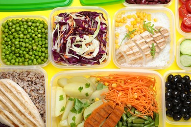 Set of plastic containers with fresh food on yellow background, flat lay