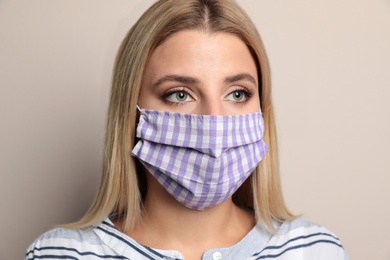 Photo of Young woman in protective face mask on beige background