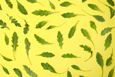 Fresh arugula leaves on yellow background, flat lay