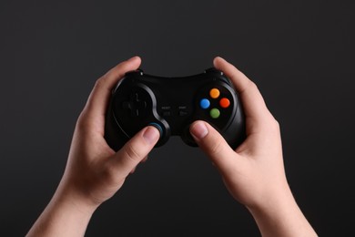 Photo of Woman using wireless game controller on dark background, closeup