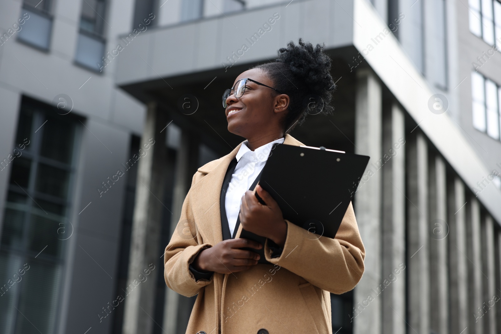 Photo of Happy woman with clipboard outdoors. Lawyer, businesswoman, accountant or manager