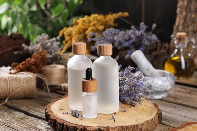 Photo of Bottles of essential oils and dry lavender flowers on wooden table. Medicinal herbs