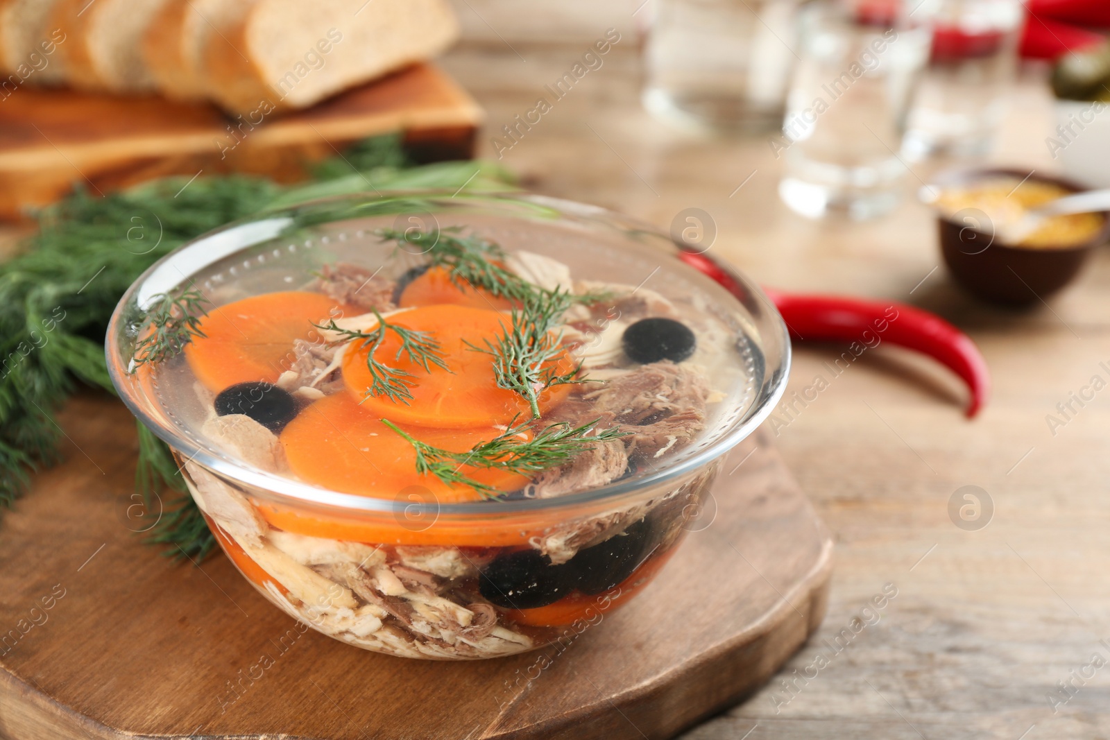 Photo of Delicious aspic with meat in bowl on wooden table, closeup