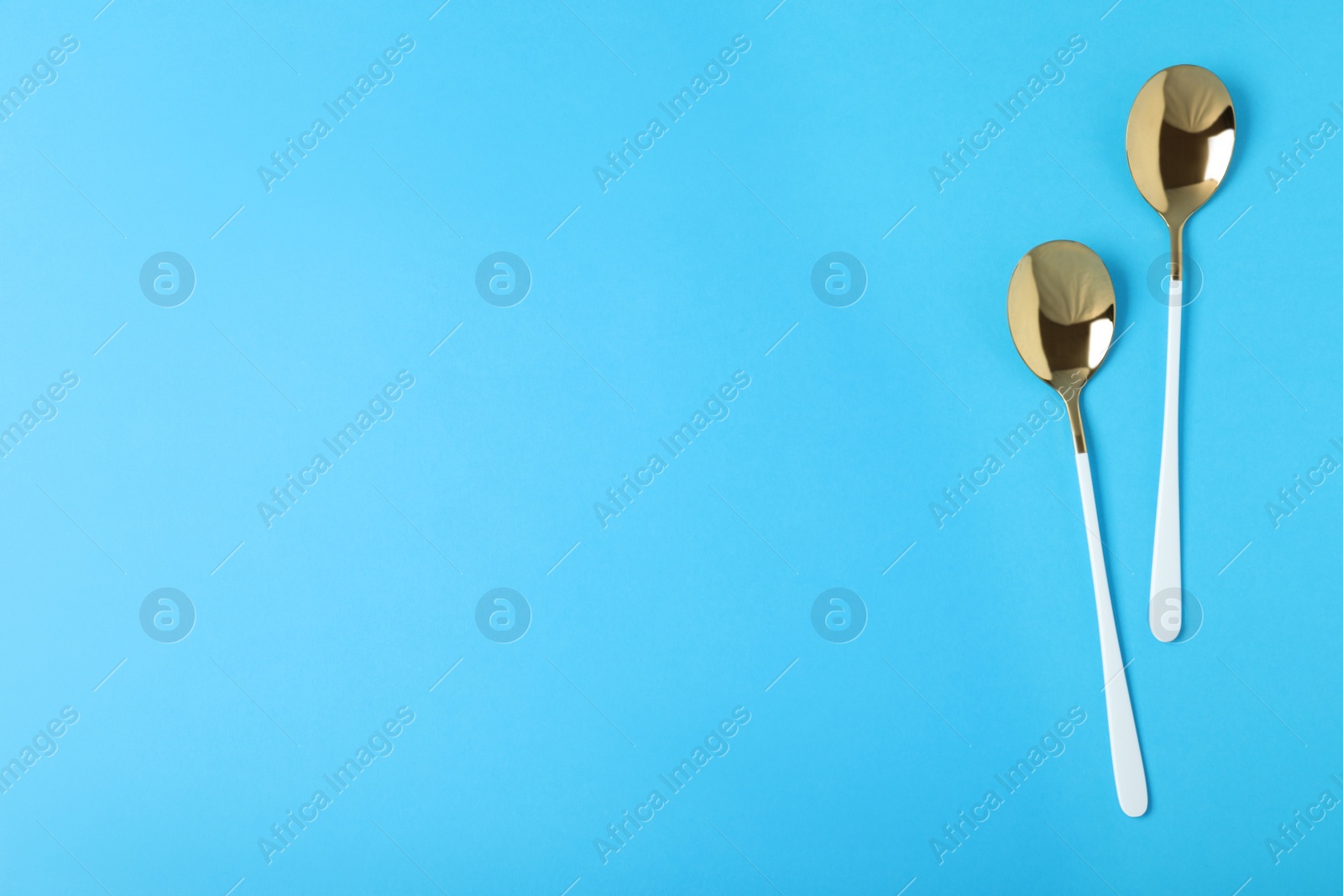 Photo of New luxury spoons on blue background, flat lay with space for text