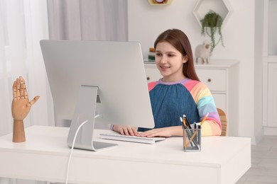 Photo of Cute girl using computer at desk in room. Home workplace