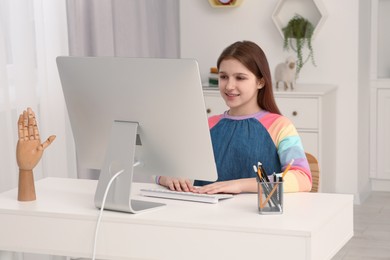 Cute girl using computer at desk in room. Home workplace