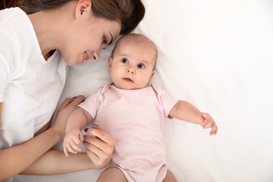 Photo of Portrait of mother with her cute baby lying on bed, top view