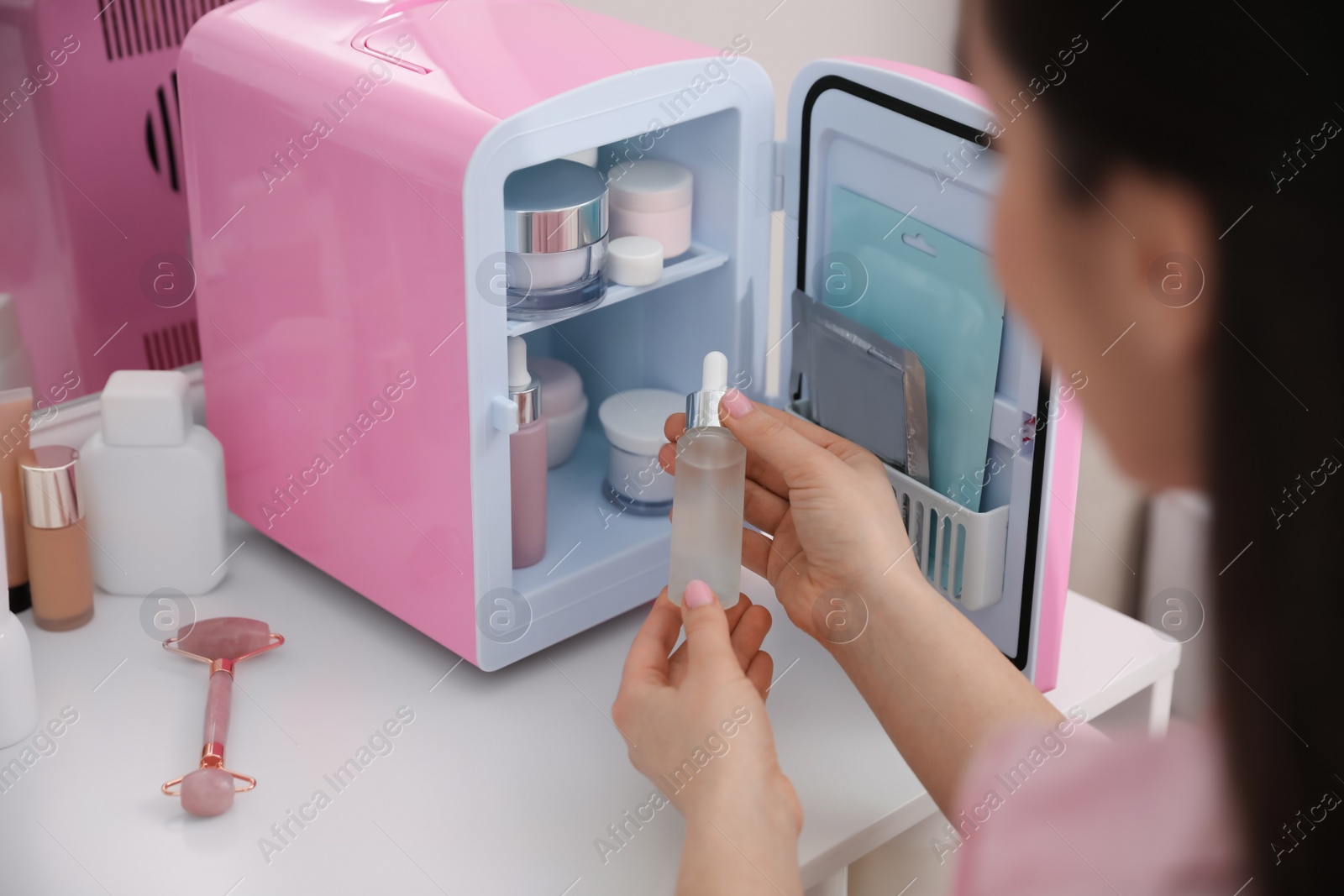 Photo of Woman taking cosmetic product out of mini refrigerator indoors, closeup