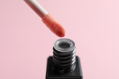 Applicator above liquid lipstick tube on color background