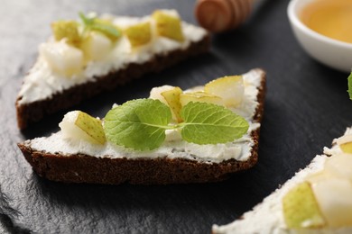 Photo of Delicious bruschetta with ricotta cheese, pear and mint on dark table, closeup