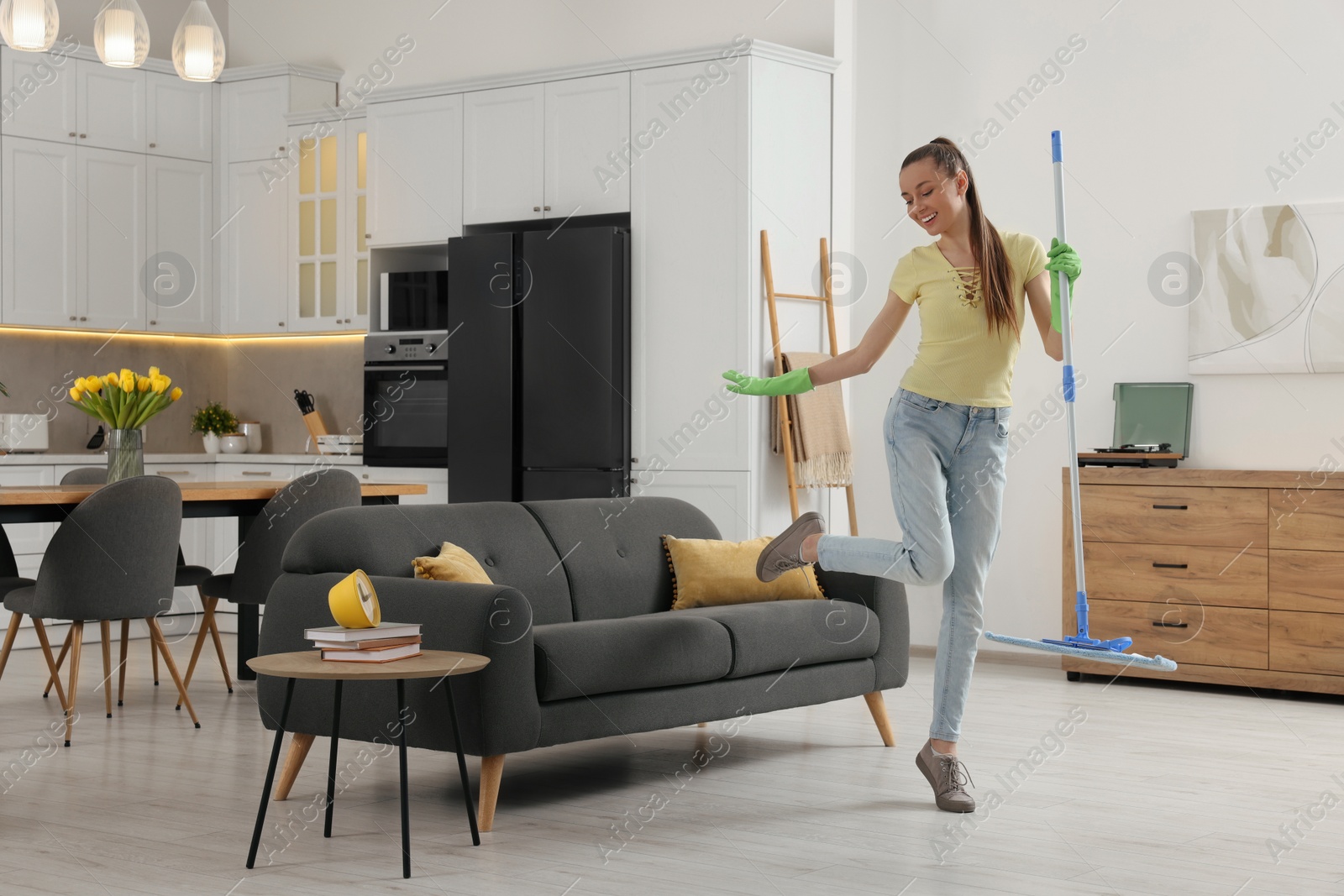 Photo of Spring cleaning. Young woman with mop dancing while tidying up at home