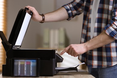 Photo of Man using modern multifunction printer in office, closeup