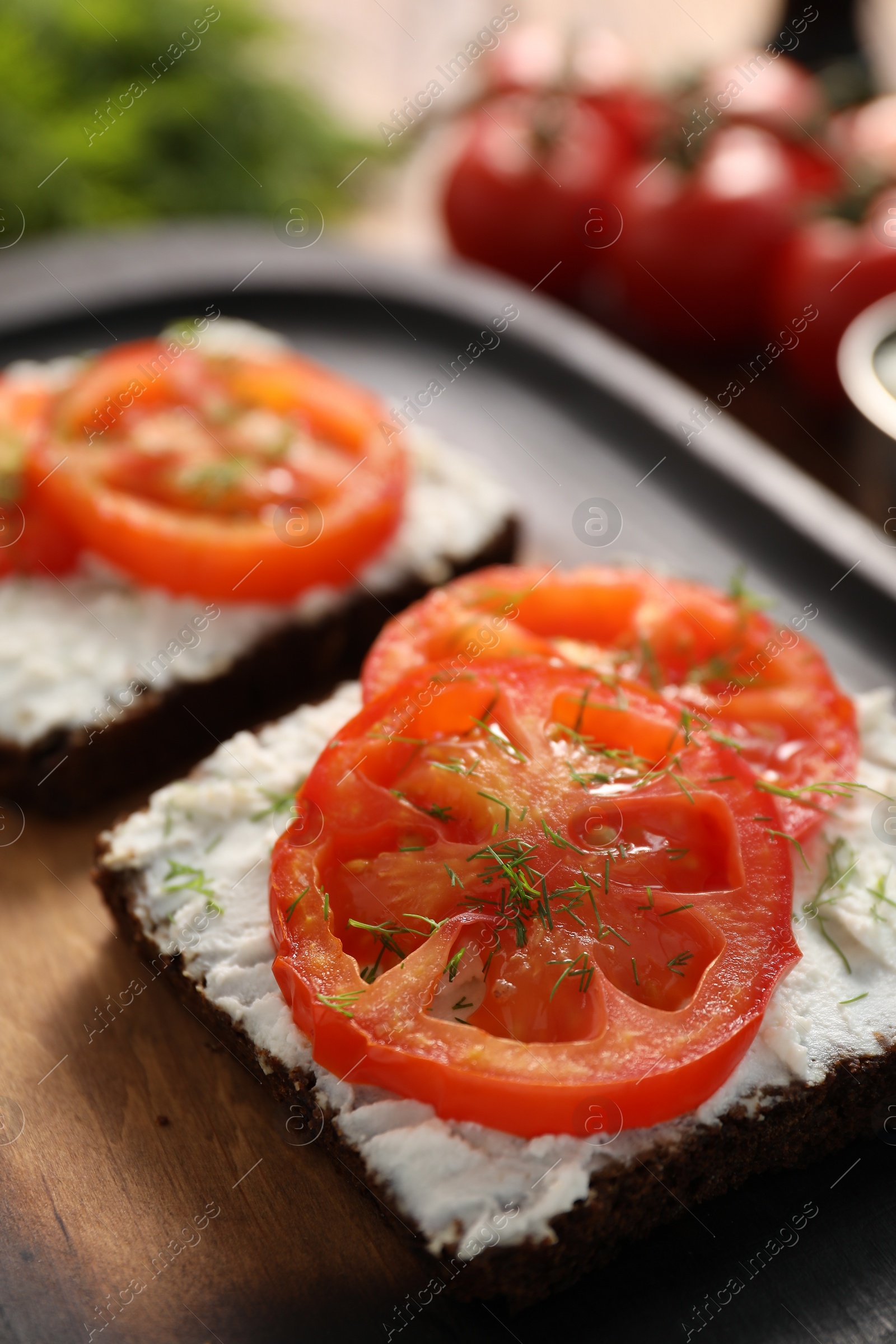 Photo of Delicious ricotta bruschettas with sliced tomatoes and dill on wooden table, closeup