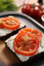 Delicious ricotta bruschettas with sliced tomatoes and dill on wooden table, closeup