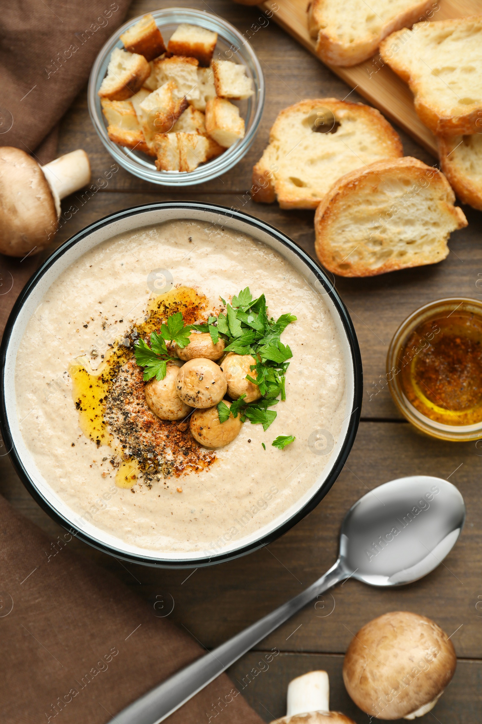 Photo of Delicious cream soup with mushrooms and ingredients on wooden table, flat lay