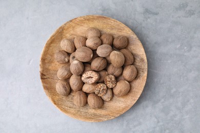 Wooden board with nutmegs on light grey table, top view