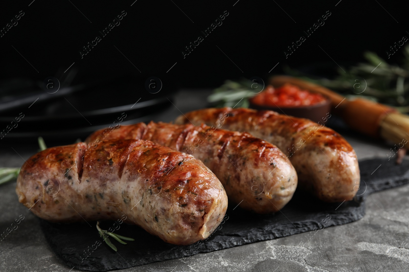 Photo of Tasty grilled sausages served on grey table