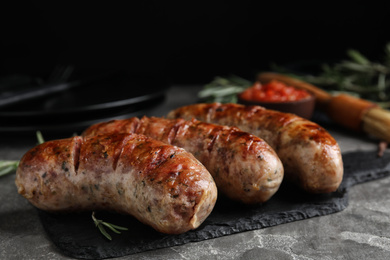 Tasty grilled sausages served on grey table