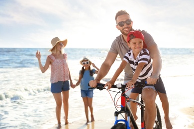 Photo of Happy family with bicycle on beach near sea