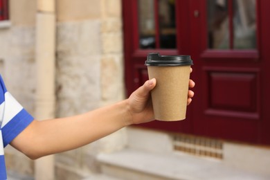 Coffee to go. Woman with paper cup of drink outdoors, closeup