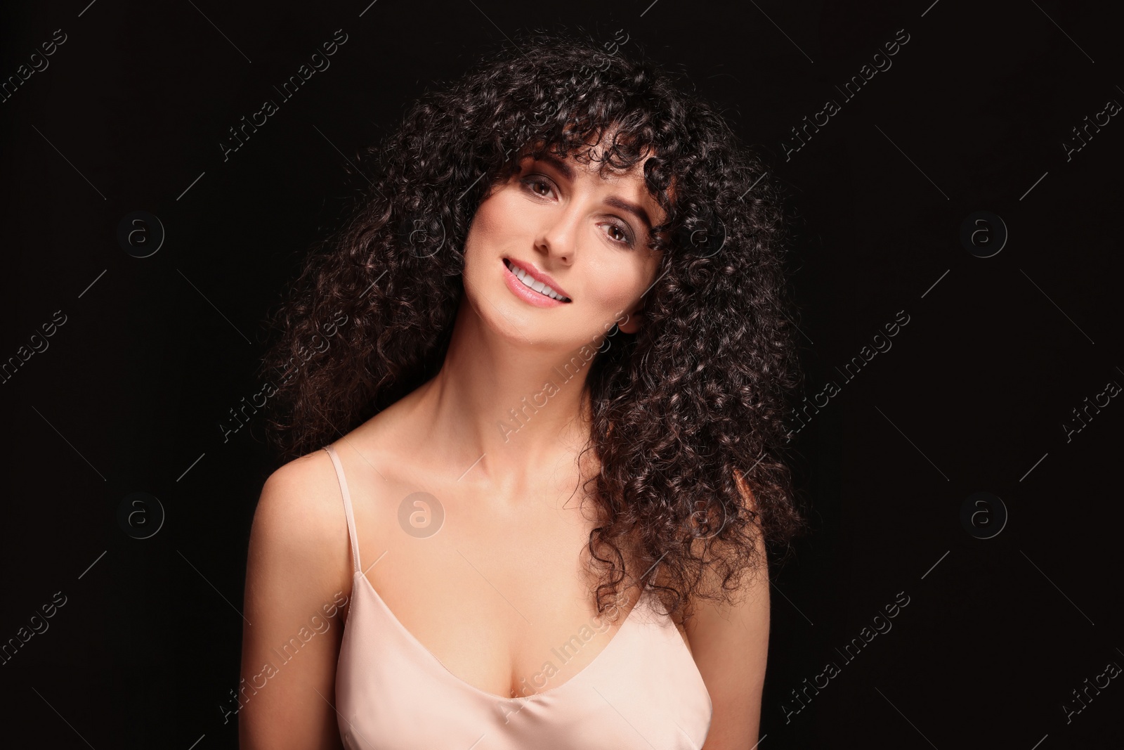 Photo of Beautiful young woman with long curly hair on black background