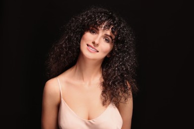 Beautiful young woman with long curly hair on black background