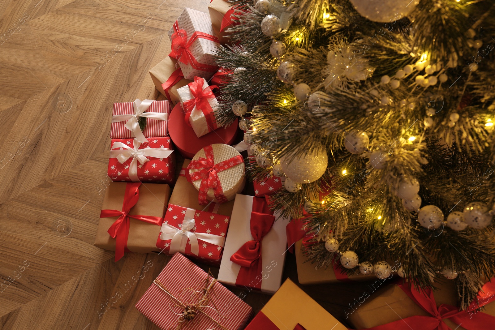 Photo of Pile of gift boxes near beautiful Christmas tree indoors