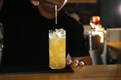 Photo of Bartender making delicious cocktail with vodka at wooden counter in bar, closeup