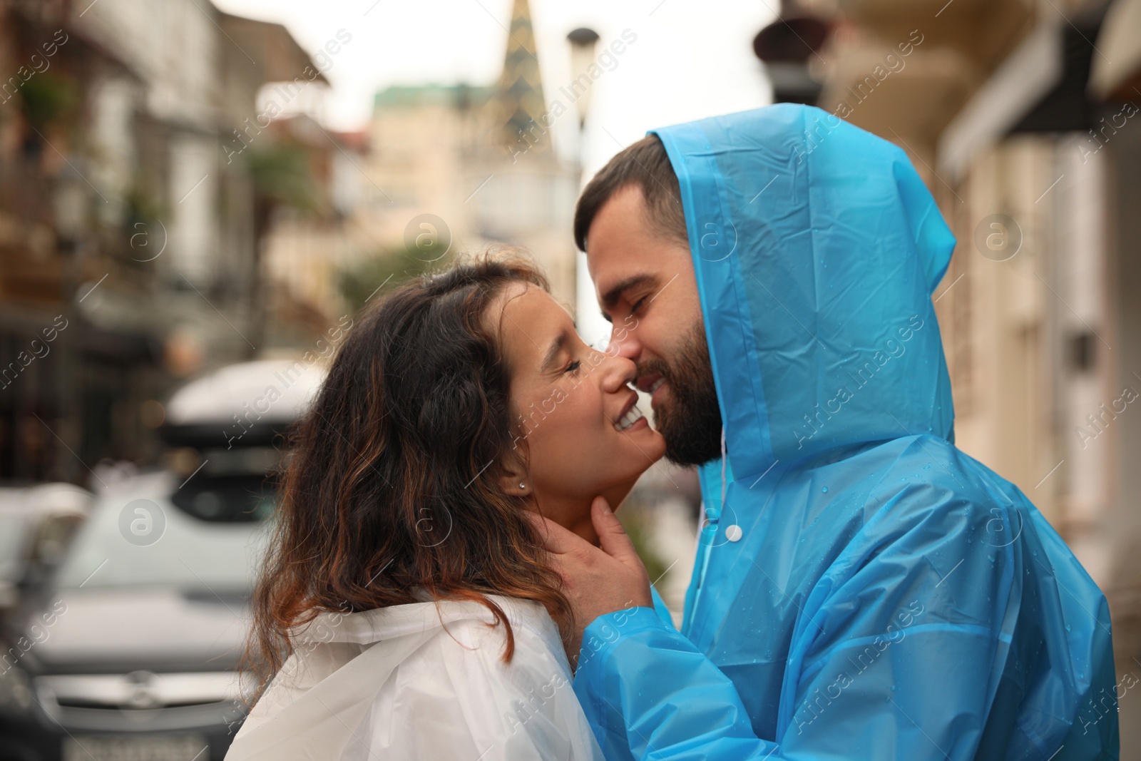 Photo of Young couple in raincoats enjoying time together on city street