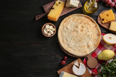 Photo of Flat lay composition with pizza crust and fresh ingredients on black wooden table. Space for text